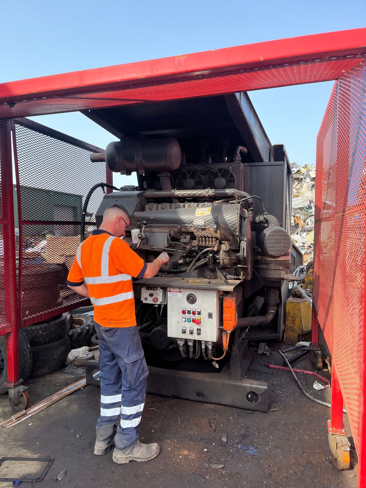 Yard operative in hi-vis working on plant machinery