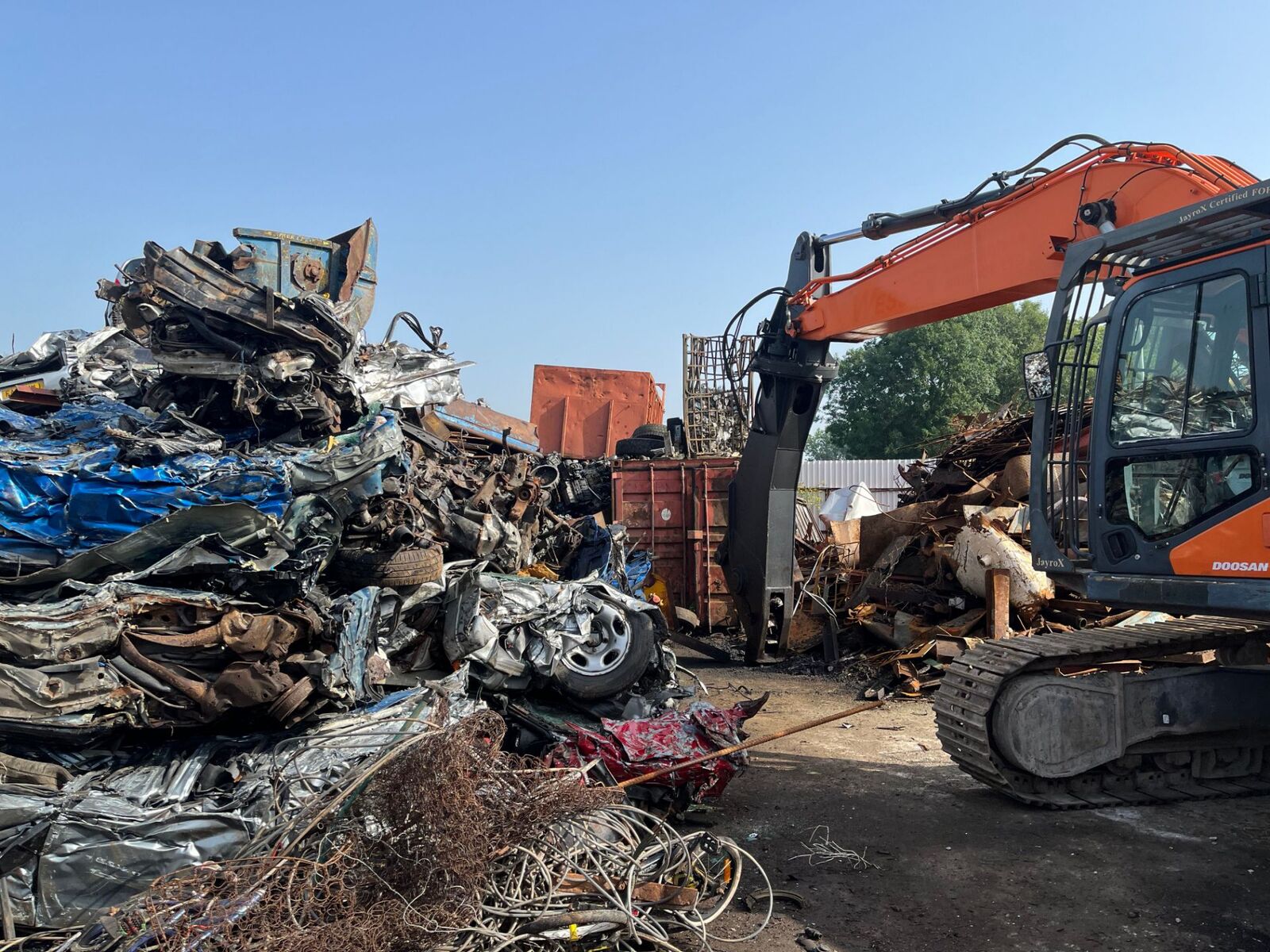 Excavator behind a large pile of mixed scrap metal