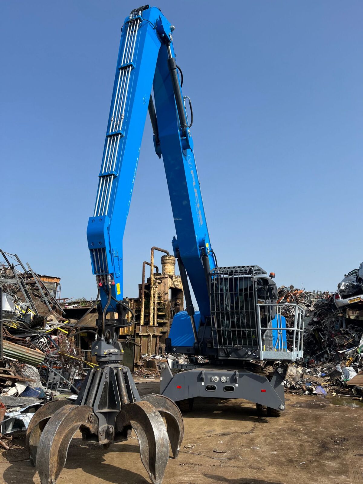 Material handler with its boom raised and grab open